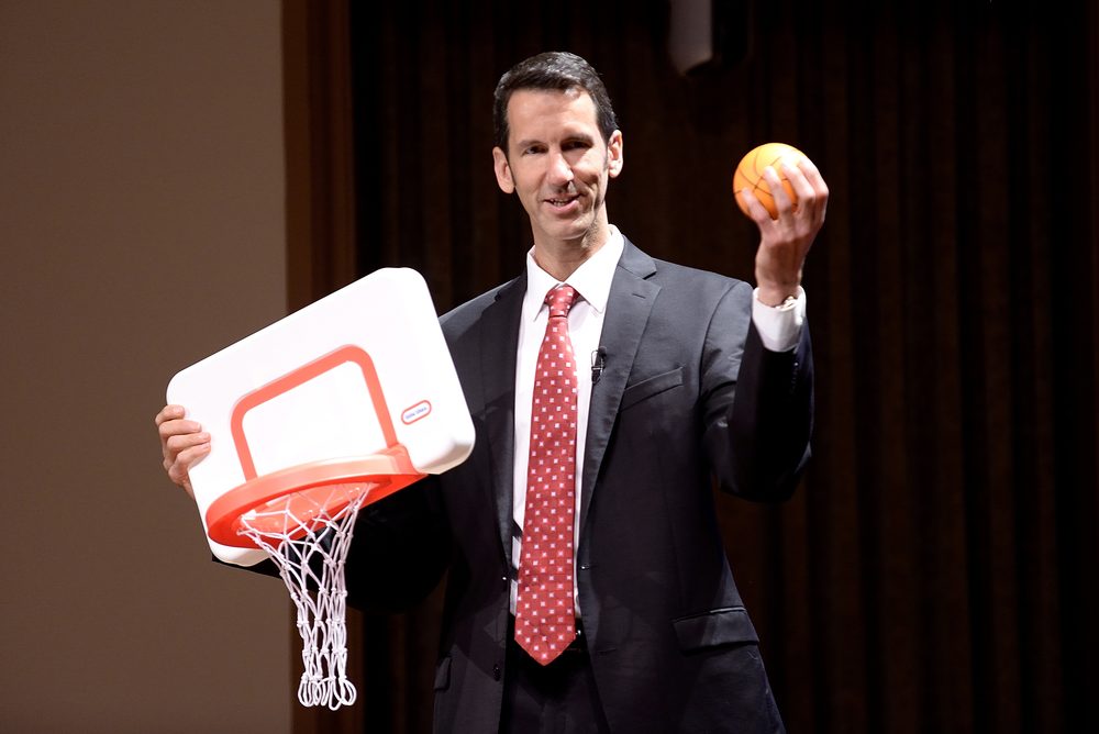R. Michael Anderson on stage holding a miniature basketball and hoop